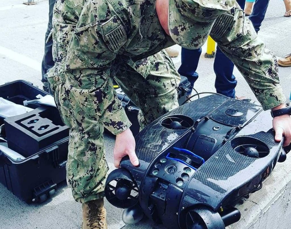 ROV Révolution Deep Trekker prêt à être déployé par un opérationnel en tenue kaki, illustrant son utilisation pour des missions sous-marines dans des conditions rigoureuses.